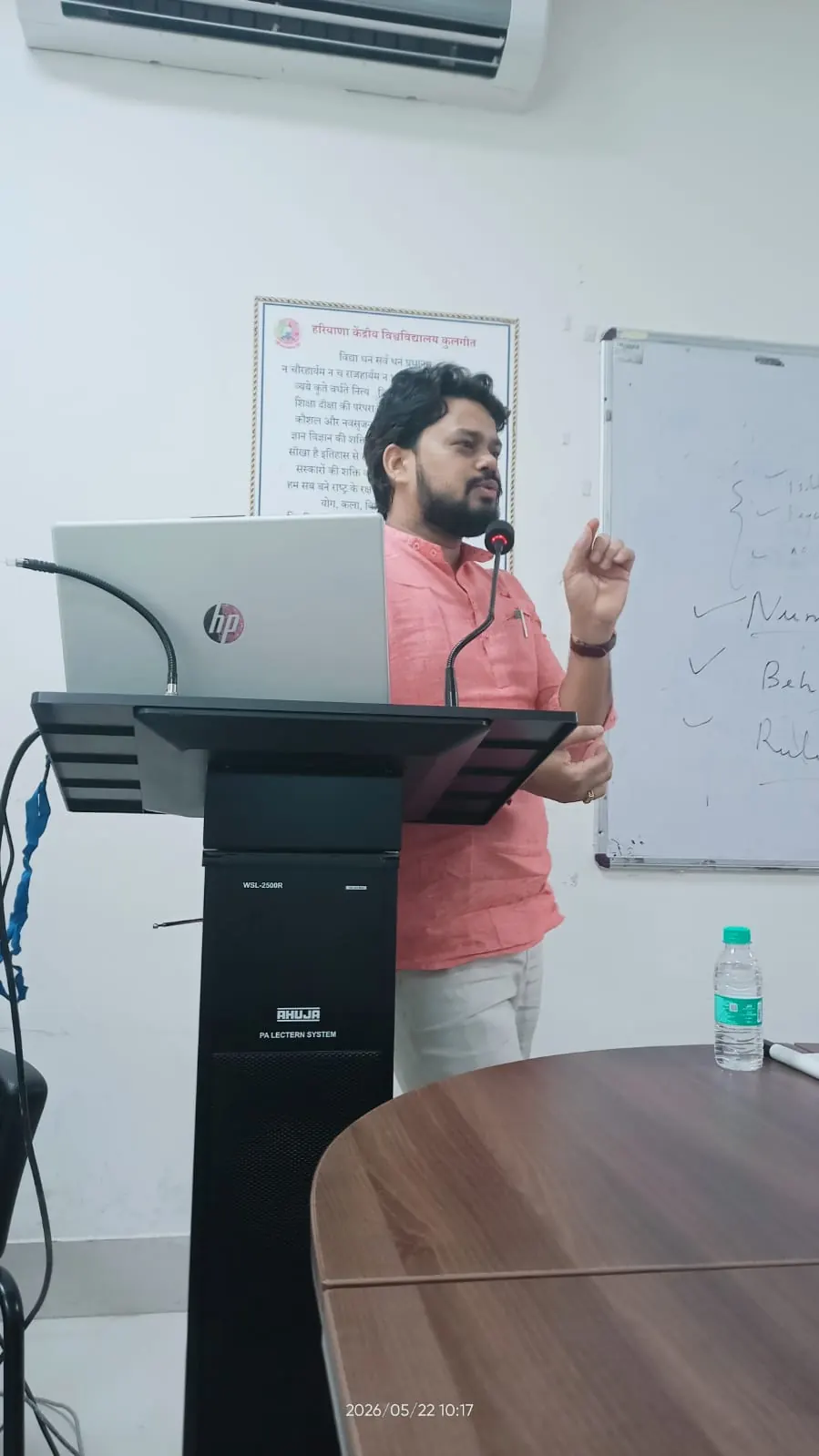 Dr. Harish Pandey delivering a lecture from a podium beside a whiteboard